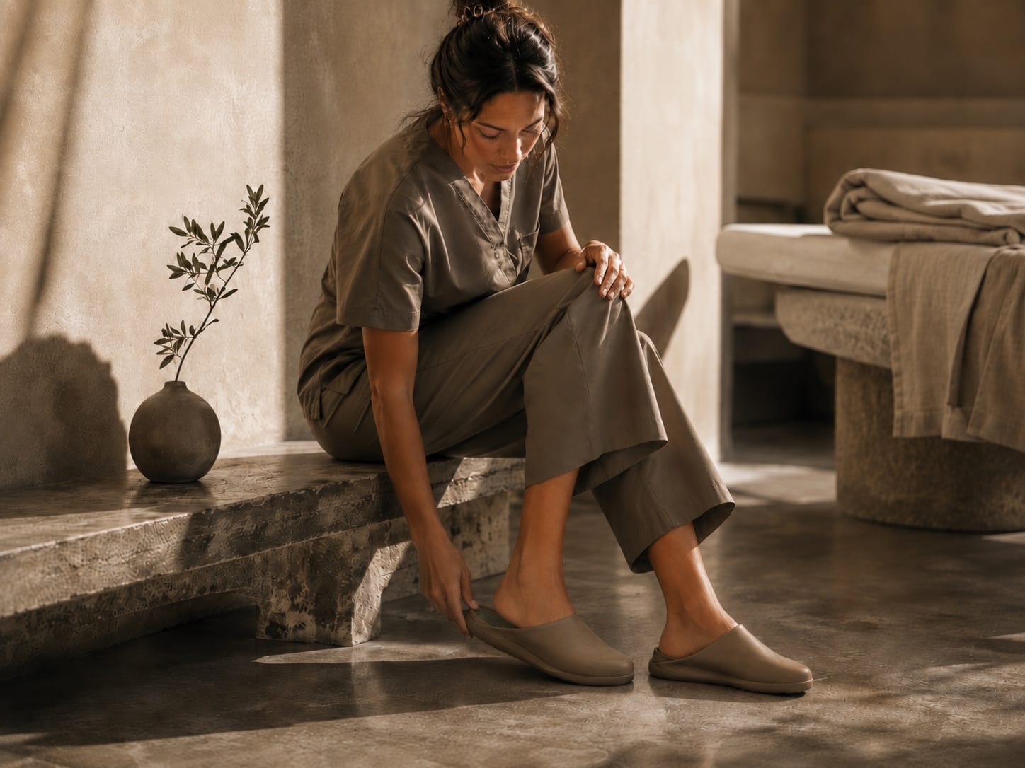 A practitioner in a calm treatment room, easing on a taupe Inyo mule.